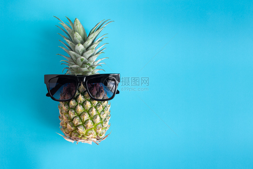 躺着蓝色底菠萝上的黑色太阳镜中时尚的夏季菠萝用于暑假和聚会概念目的有机图片
