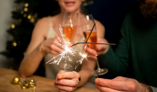 灯幸福的情侣拿着火花和香槟杯新年派对黑色的朋友们图片