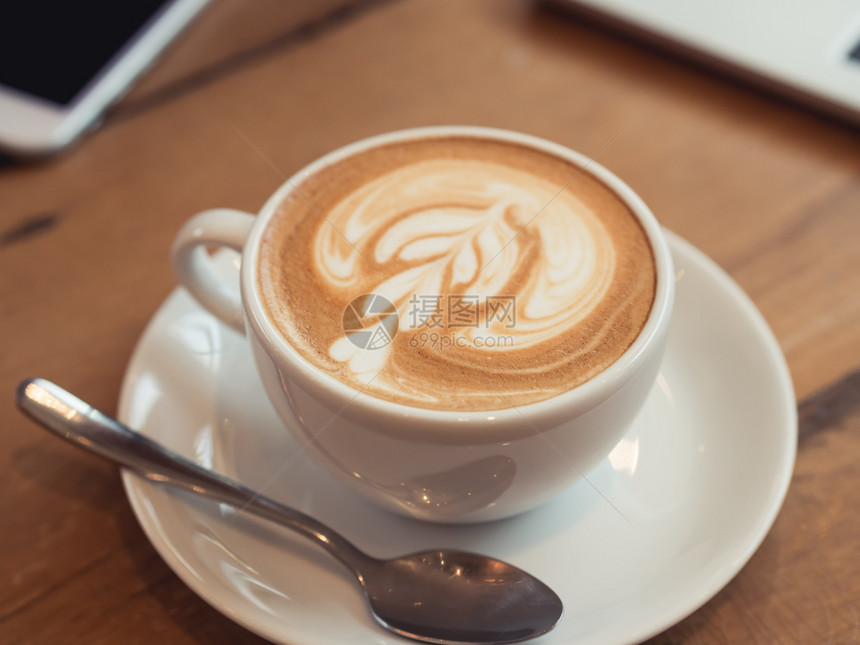 卡布奇诺牛奶白色的在咖啡厅木桌上用拿铁艺术把白色咖啡杯贴上图片