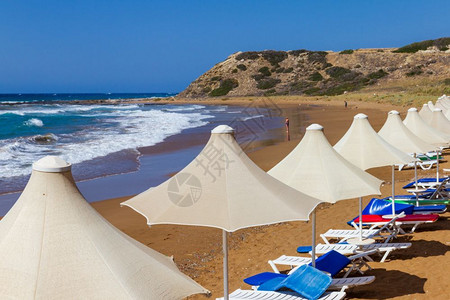 贝达夫放松塞浦路斯岛Davlos海滩的一排雨伞和防晒床美丽的户外背景