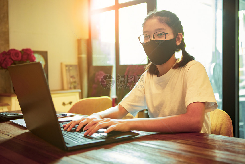 女互联网身戴保护面罩的亚洲青少年在电脑笔记本在家工作上打字学习图片
