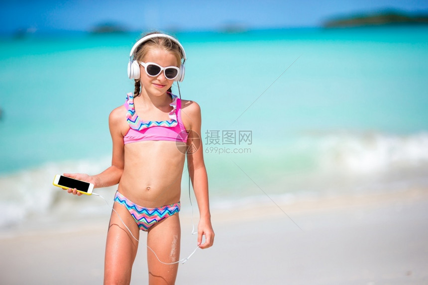 孩子播放器安提瓜小可爱的女孩在海滩上听音乐小女孩在海滩上用耳机沙图片