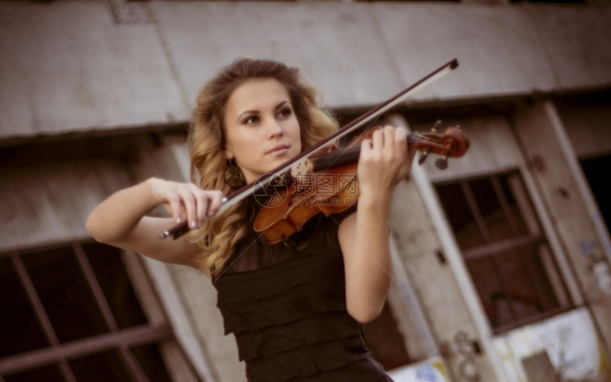 年轻女子在户外演奏小提琴图片