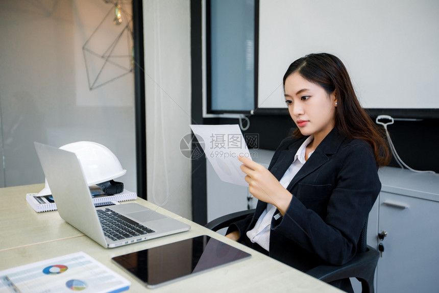 使用笔记本的亚洲商业妇女以及因工作而严重和头痛的亚洲商业妇女木制的办公室伤心图片