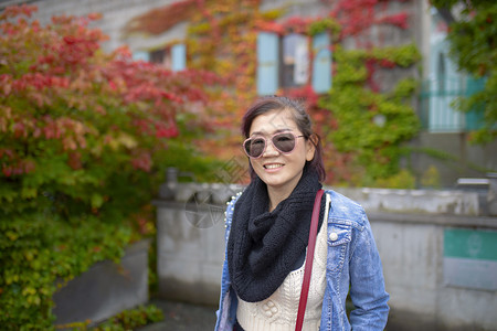 日本人京都放松带着多彩的叶子微笑脸满是齿牙的亚洲女人公园背景图片
