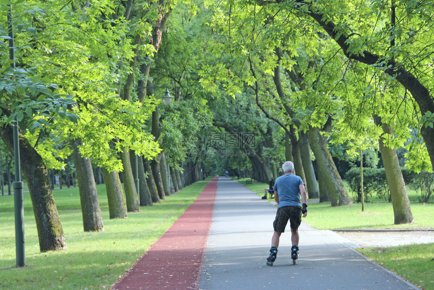 滚轴休闲的运动美丽城市公园有跑步机男人在溜冰鞋上跑步老人在城市公园里用溜冰鞋跑步城市自然健康的生活方式美丽的城市公园男人在溜冰鞋图片
