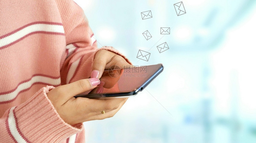 消息传递商业年轻女用智能手机发送电子邮件在蓝区域背景下内光模糊穿着粉红色毛衣紧的年轻女手士图片