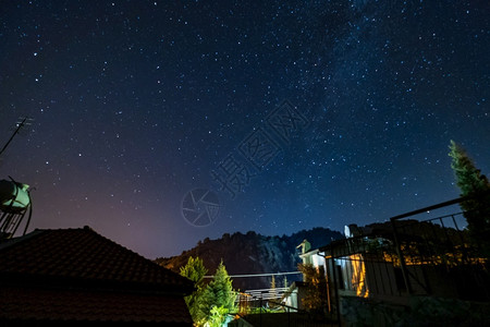 特罗多斯乳白色卡科佩特里亚森林上空的恒星和银河系以及塞浦路斯Kakopetria村Troodos山上的一座房子背景