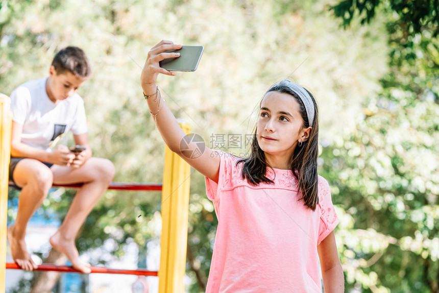 服用女孩带着手机在公园里拍自技术愉快图片