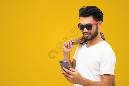男无线的亚洲商人英俊帅哥长胡子微笑在黄色背景下使用智能手机沟通图片