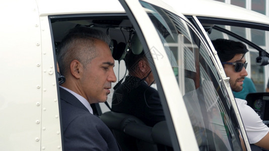 一种商人和驾驶小型私直升机的驾驶员停靠在着陆点运输直升机场图片