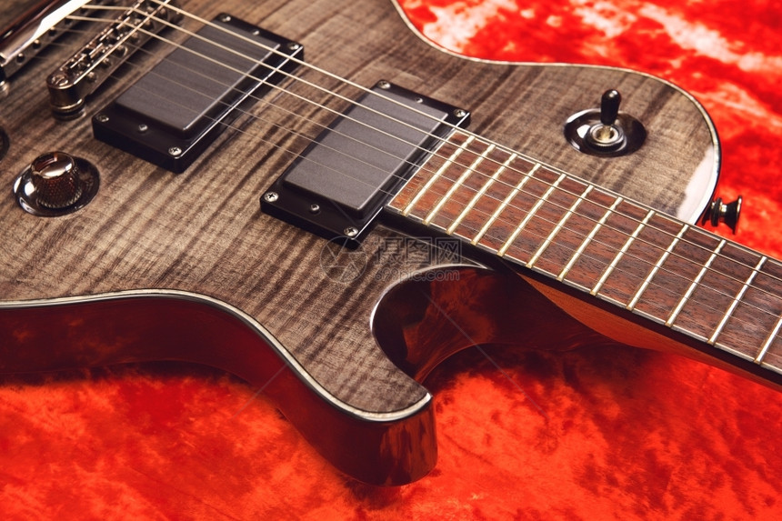 现代的木头红色天鹅绒背景的黑电吉他乐器图片