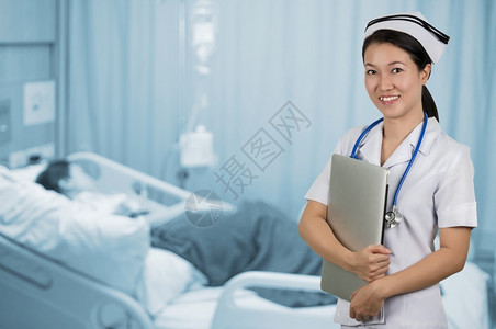 亚洲护士持有笔记本和背景模糊的病人室亚洲护士吸引人的医院年轻图片