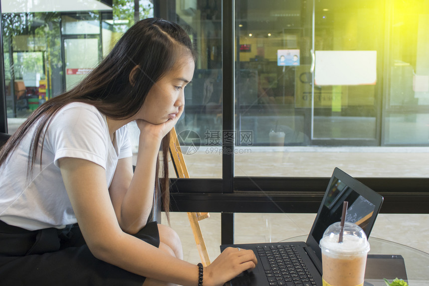 在咖啡馆用笔记本电脑工作的亚洲妇女孩在线的屏幕图片