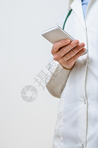 女一种名医生在务室用智能手机发短信一名女医生在务室用智能电话发短信舍纳塔根背景图片