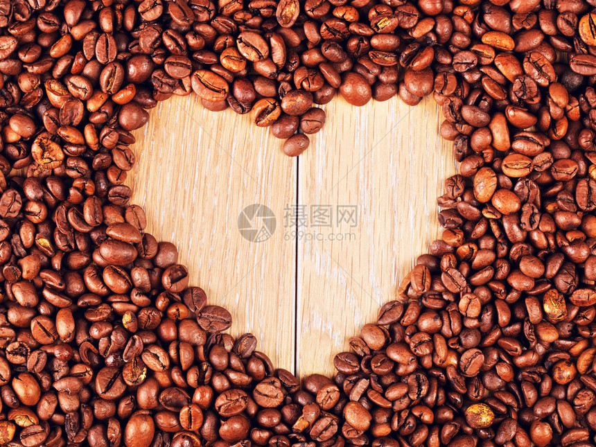 木制桌上的心形咖啡豆背景图片
