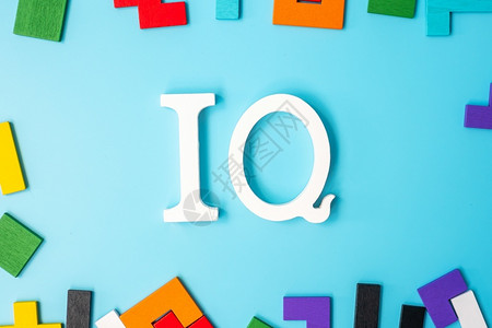 情商低制造智力谜IQ文本包含色彩多的木质拼图片蓝背景的几何形状块以及智慧商数和逻辑思维概念设计图片