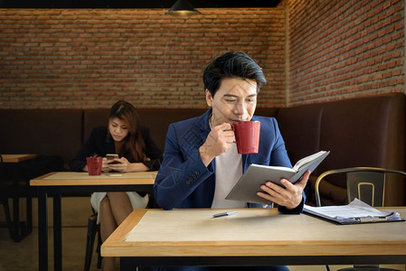 沟通工作场所在办公室喝红杯咖啡时工作着的年轻青商人桌子图片