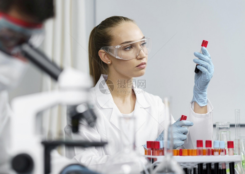 带有测试管安全眼镜的女研究员化验室男同事卫生保健化学手套图片