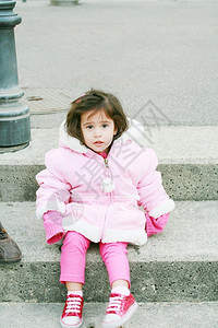 户外坐在台阶上穿着粉色衣服的小女孩图片
