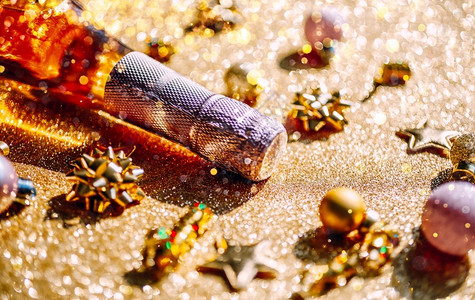 圣诞或新年配有一瓶玫瑰香槟和金色闪亮背景的花彩装饰喜庆布基和影子的侧观以及庆祝党的创造概念以庆祝圣诞节或新年阴影微光饮料背景图片