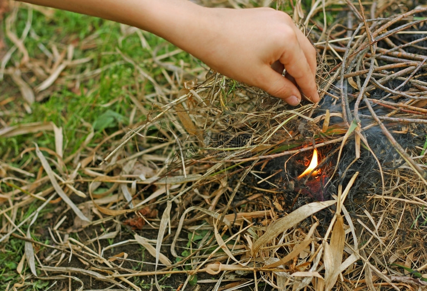 火花焰一种个人的手他在林中干枯的叶子在旱季人们点燃烈火图片