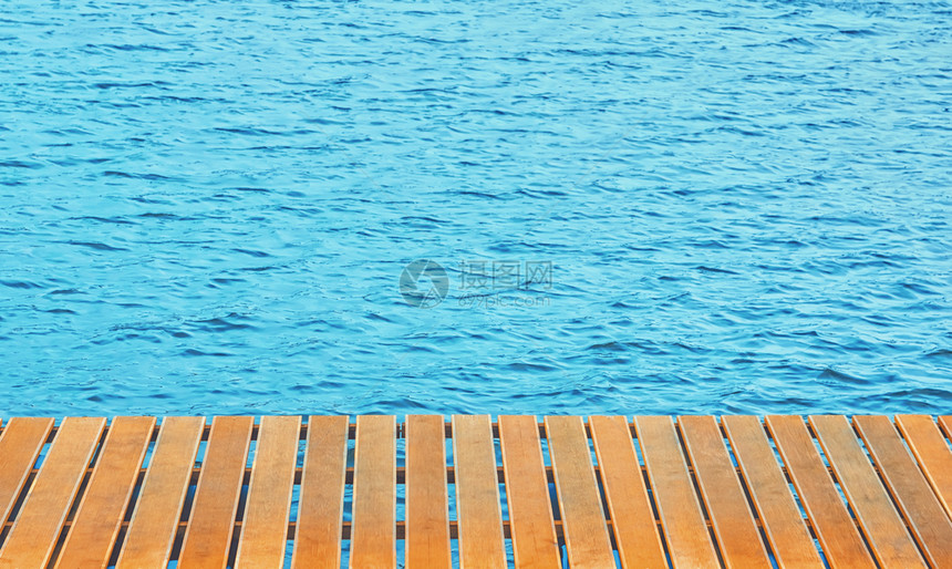 场景海洋蓝色波纹上方码头的橙色木阳台板背景有空间复制海面码头背景空的晴天图片