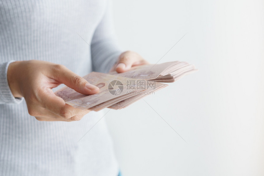 税亚裔妇女用手在白背景上数钱她手里拿着泰兰的货币铢经济现金图片