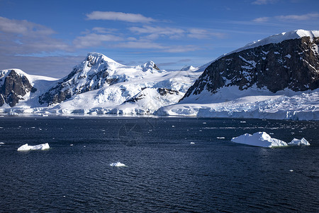 蓝海冰山正面水在蓝海前有冰雪的山峰南极洲也有大片冰块分层的背景