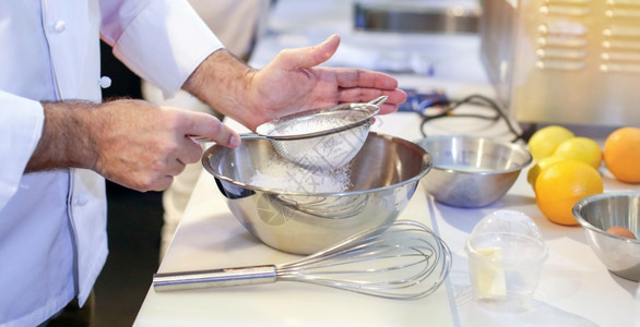 糕点厨师贝克将面粉切成包店厨房的碗一种手桌子图片