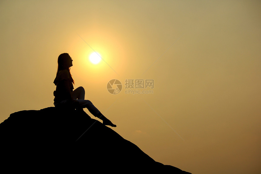 日落户外女士坐在岩石上的女人休眠图片