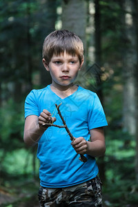 蓝色的木头走夏天森林里有临时弹弓的帅气男孩图片