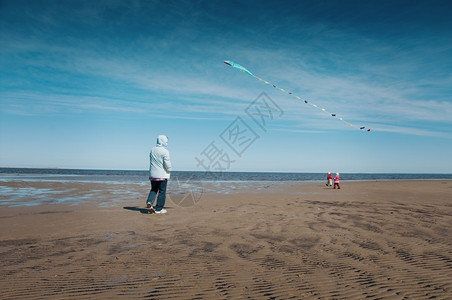 户外快乐的母亲和女儿在沿海上放风筝阳光图片
