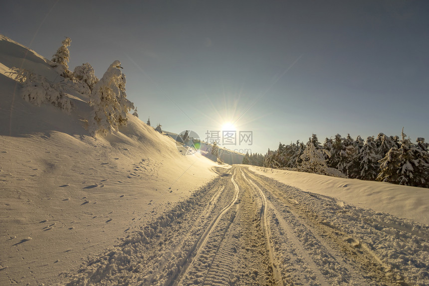 冰冷经过冬季山峰天的路上有太阳雪和汽车足迹的风景冬季乘车旅行的概念户外图片