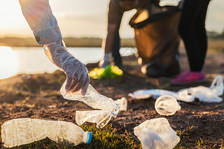 在日落的公园河将垃圾塑料瓶装在黑袋里的人志愿者环境橡胶地球图片