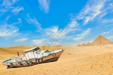 荒漠化在沙金字塔附近埃及沙漠的旧弃船在沙漠中的金字塔附近沙丘破坏图片