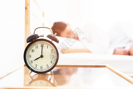 床头早期的商业与睡妇女一起在床上休息的闹钟放假时间懒惰的概念图片