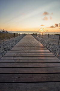 太阳浪漫的海日落时去荷兰海滩的木步行道图片