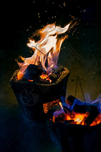 在黑暗抽象背景下燃烧木炭的火焰和花与bokeh自然余烬耀斑图片