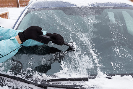 白色的女人在冬天从车里打扫雪辆冰图片