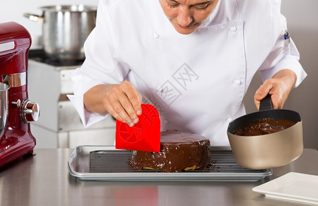配料釉面准备厨房的糕点师装饰巧克力蛋糕图片