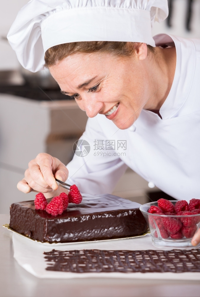 厨房的糕点师装饰巧克力蛋糕可黑色的糖霜图片