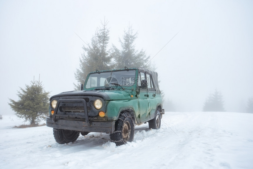 雾中雪山上的绿色越野车雪山上的绿色越野车追踪轮辆图片