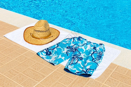 游泳池浴巾上帽子和泳裤图片
