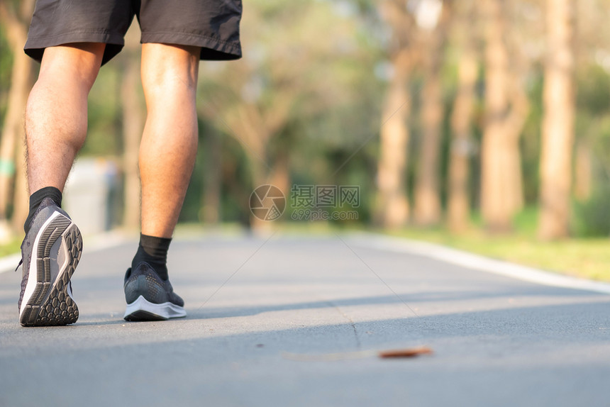 拉伸搭售训练在公园露户外运动场上行走的年轻健身男子腿在公园中步行男跑者在亚洲运动员阳光照耀的早晨漫步和徒田径前的道路上跑动体育健图片