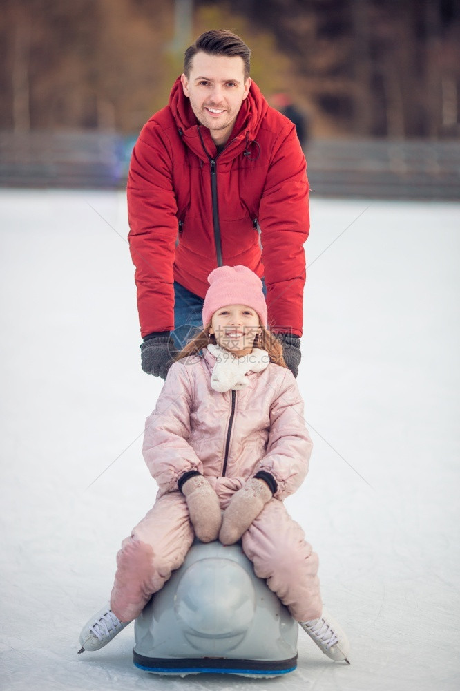 家庭冬季运动在溜冰场滑父亲和女儿在冬日孩户外娱乐图片