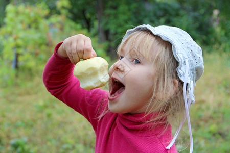 嘴吃年轻的吃苹果小宝手里拿着它手里拿着被啃过的苹果宝试图咬成熟的苹果食物肖像背景