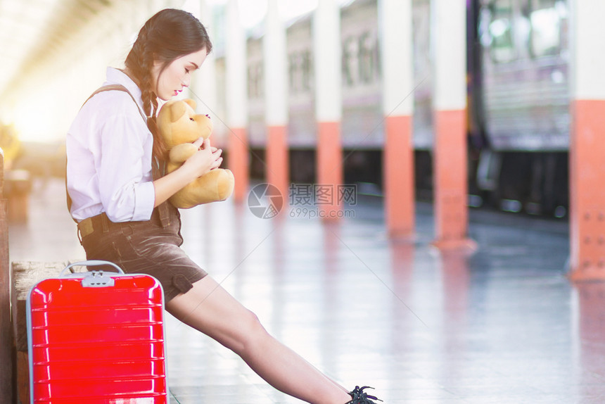 身体亚洲孕妇旅客在火车站行时抱着一个红色手提箱的泰迪熊肚皮女孩旅游家庭图片