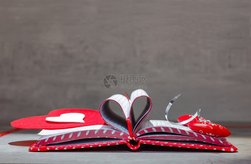 开放笔记本用折叠成心脏形状的页面打开笔记本用红白心形式的书签和笔记本放在木制桌子上红色的简单提醒图片