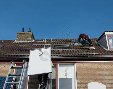 把太阳能电池板安装在屋顶上的男人图片